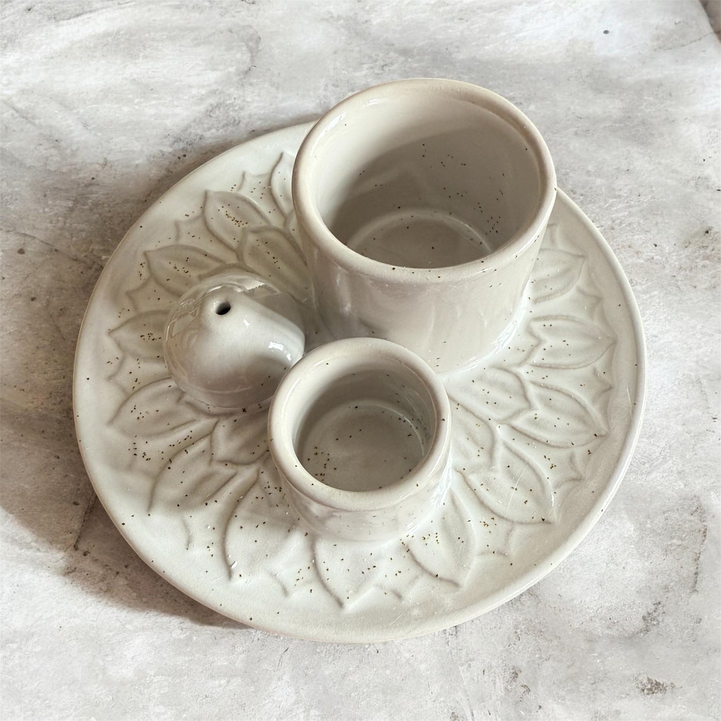 White ceramic dish with leaf patterns on a marble surface