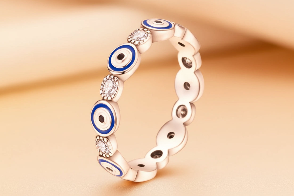 Silver ring with blue evil eye designs and clear gemstones on a white background