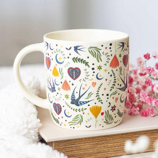 Decorative mug with colorful patterns on a white surface with flowers in the background