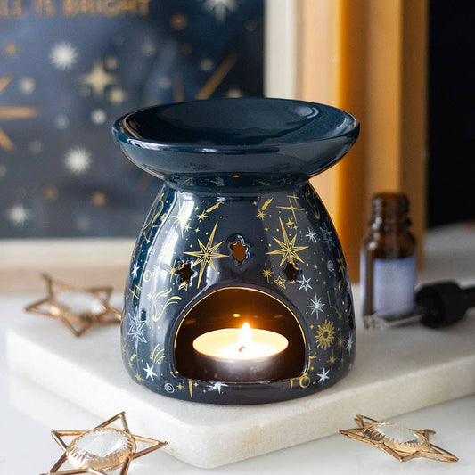 Navy blue wax warmer with a lit candle on a decorative surface with star designs.