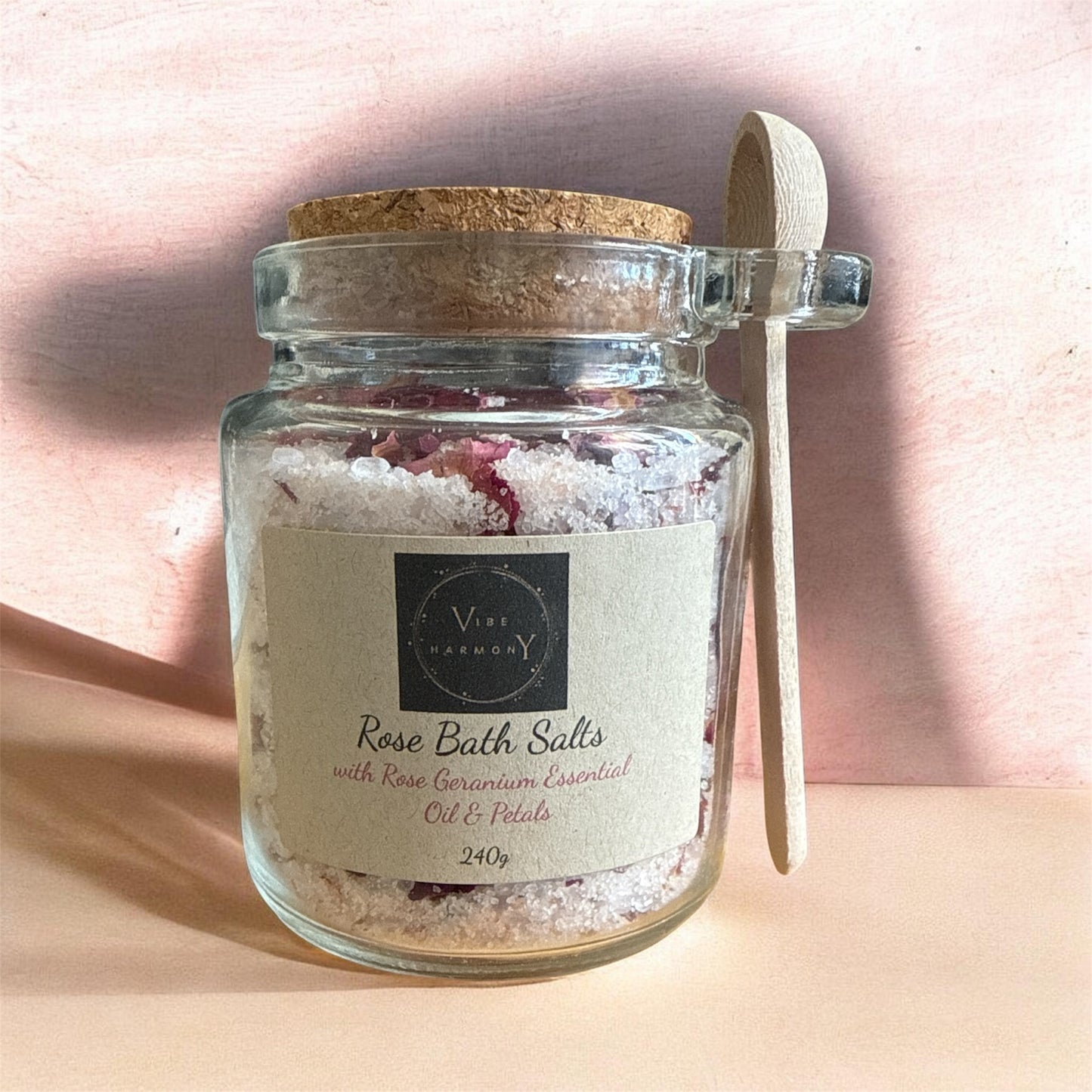 Jar of Rose Bath Salts with a wooden spoon on a soft pink background