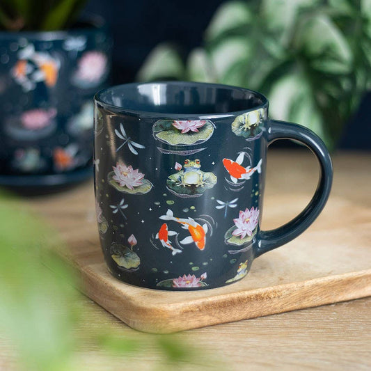Navy blue mug with koi fish and lotus design on a wooden surface