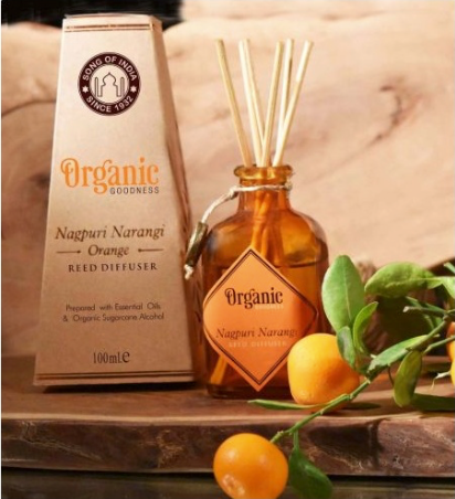 Orange-themed reed diffuser with packaging on a wooden surface