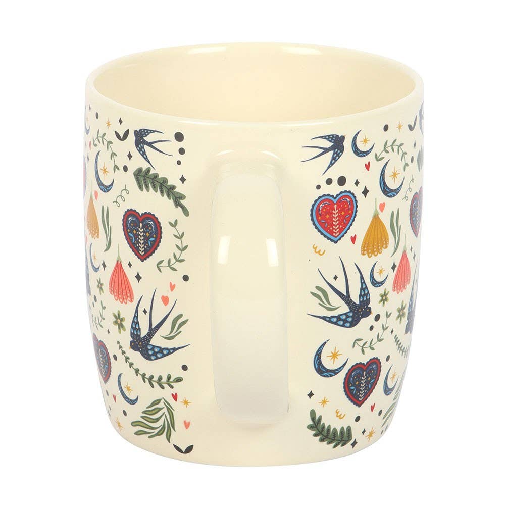 Ceramic mug with colorful heart and swallows design on a white background